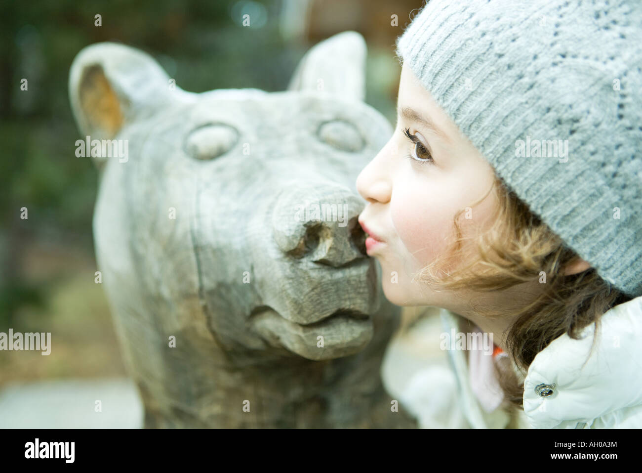 Girl kissing bear statue, side view, portrait Stock Photo