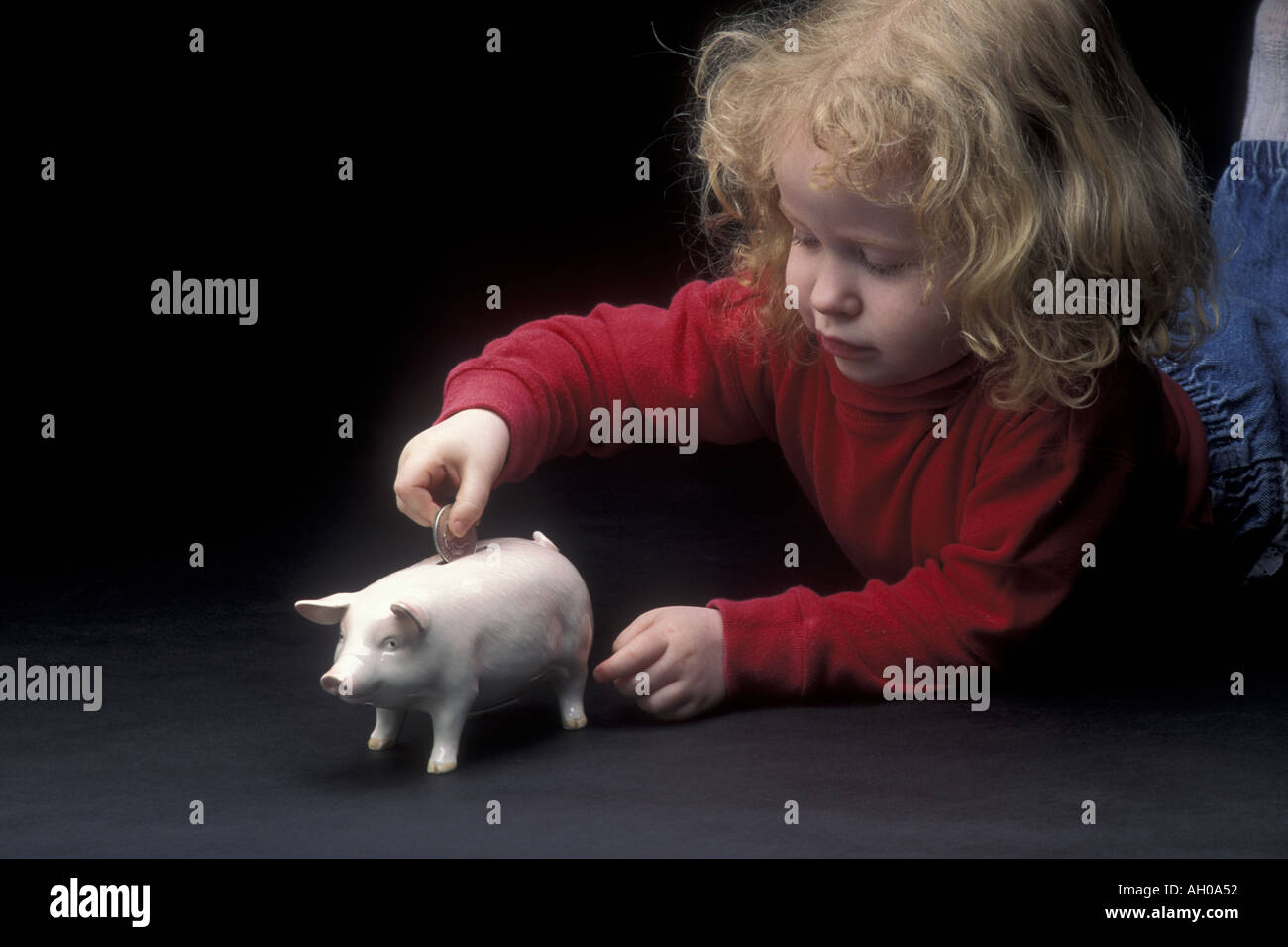 Cute little girl putting coins into piggy bank Stock Photo - Alamy