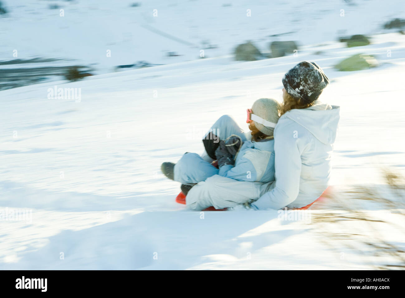 Young friends sledding down hill together, blurred motion Stock Photo