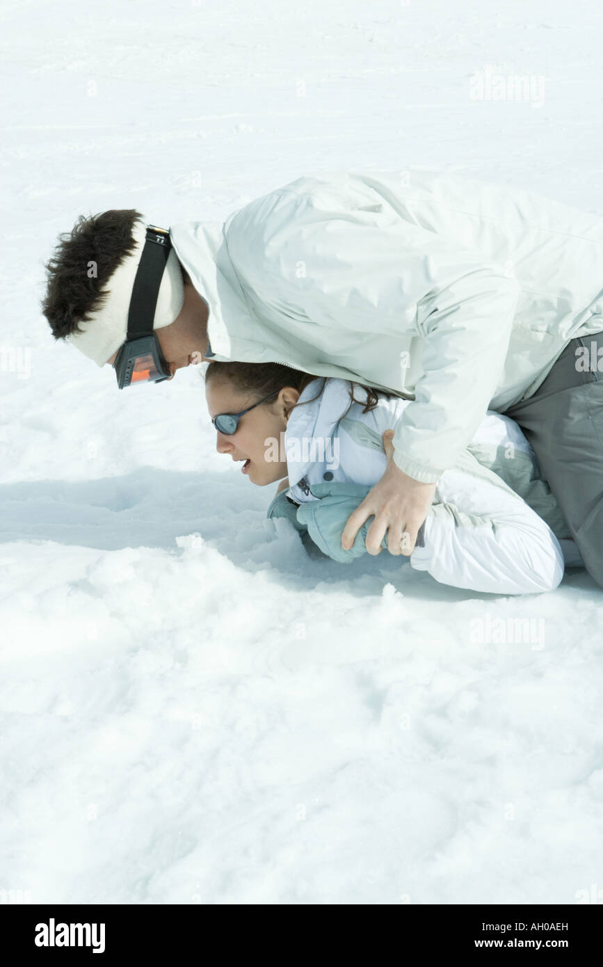 Brother and sister playing around in snow, one on top of the other ...
