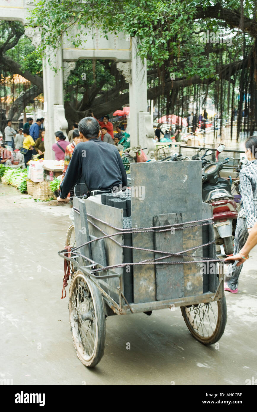 China, Guangdong province, man transporting goods to street market with rickshaw Stock Photo