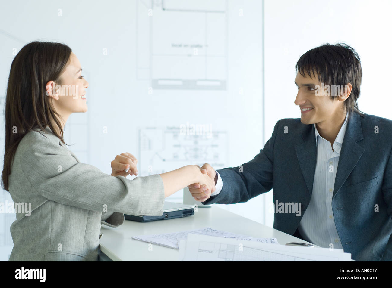 Woman and man shaking hands across table in architect firm Stock Photo