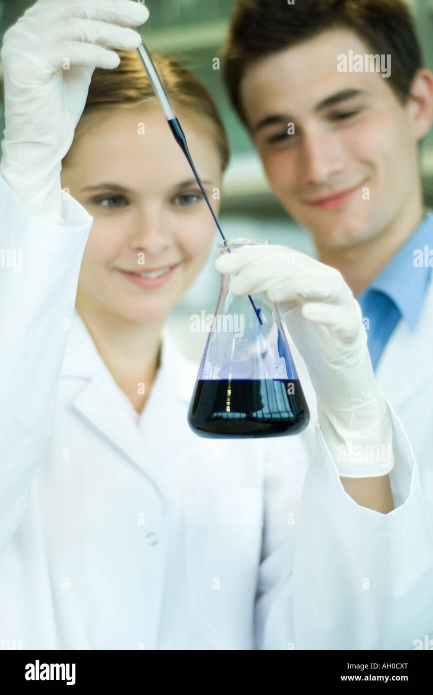 Young male and female lab workers, holding lab glassware Stock Photo