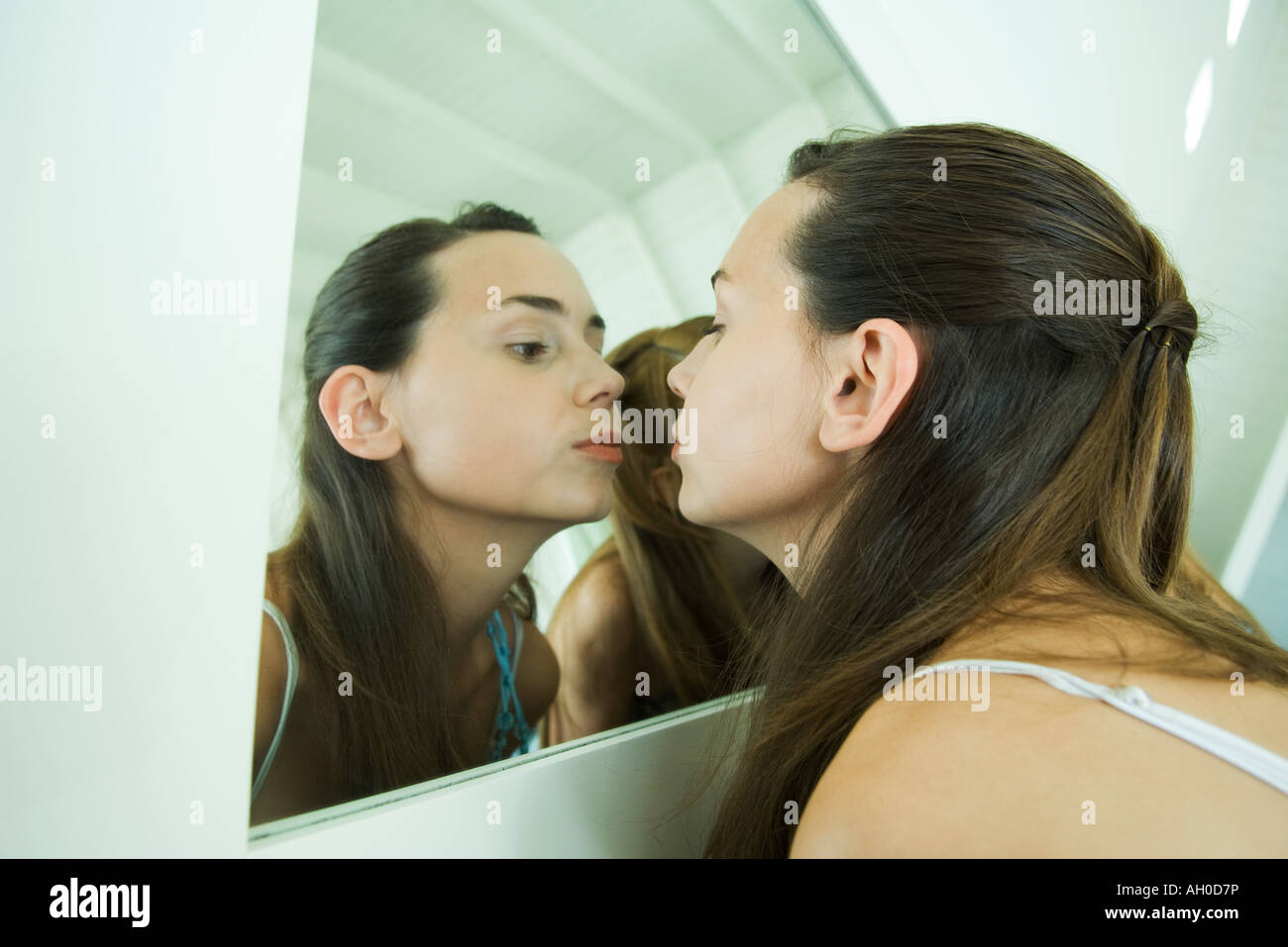 Teenage girl looking at self in mirror, kissing her reflection Stock Photo