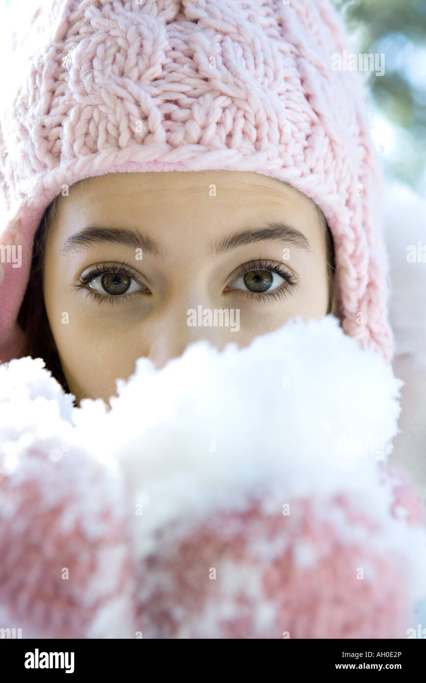 Preteen girl holding handful of snow in mittens, looking at camera Stock Photo