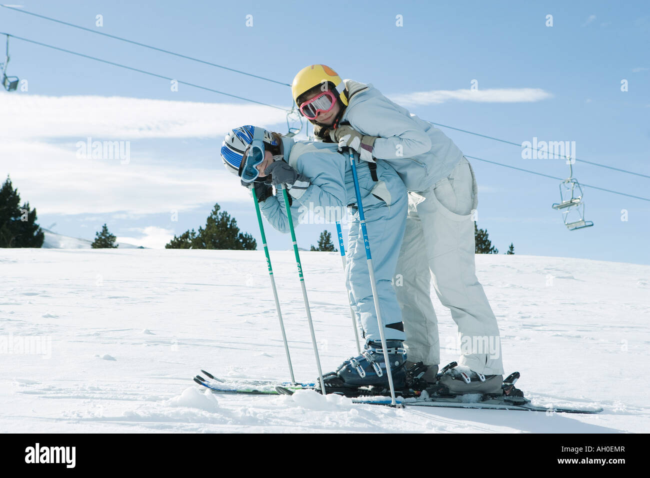 Young skiers bending over together, smiling at camera, full length portrait Stock Photo
