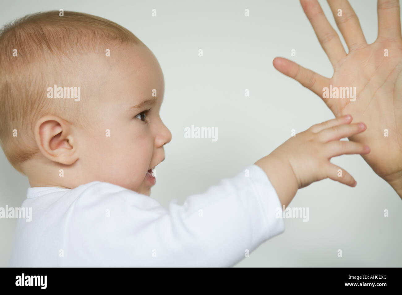 Baby reaching for adult's hand, cropped view Stock Photo