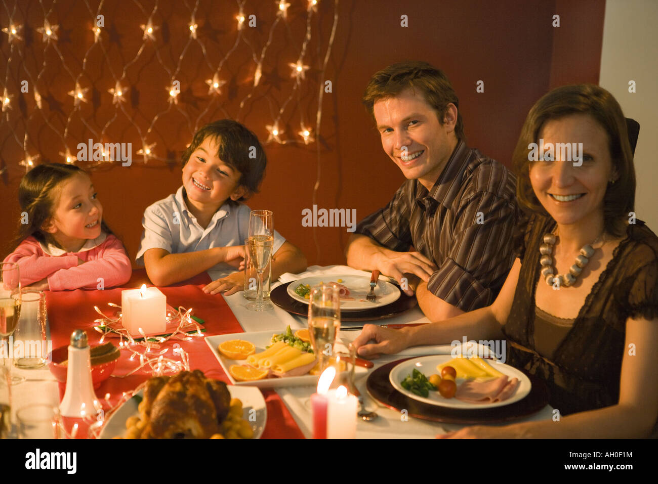 Family with two children eating festive dinner, smiling at camera Stock Photo