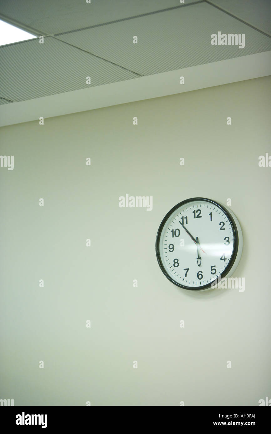 Clock hanging on wall under fluorescent light Stock Photo Alamy