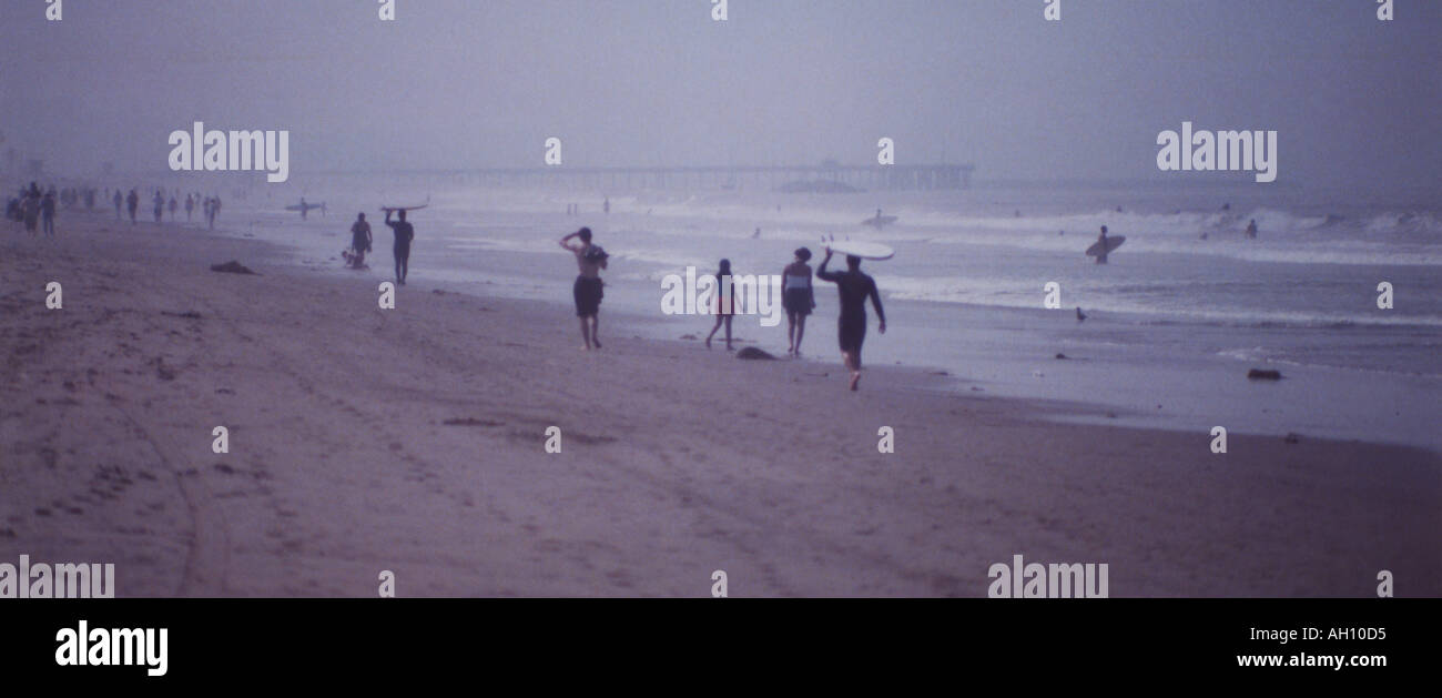 Surfers and strollers along California beach at Santa Monica with ocean haze. Stock Photo