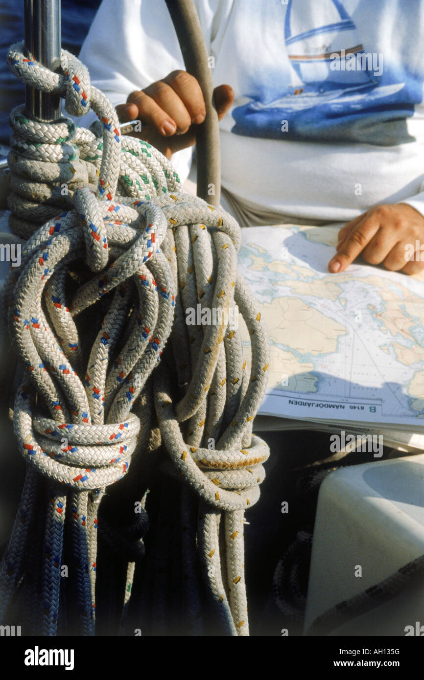 Man at helm of sailboat with compass, charts and rigging Stock Photo