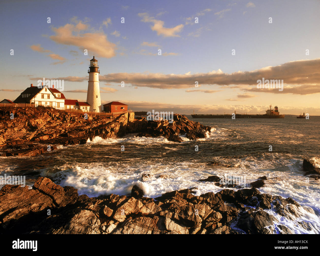 Ship passing Portland Head Lighthouse on coast of Maine at sunrise Stock Photo