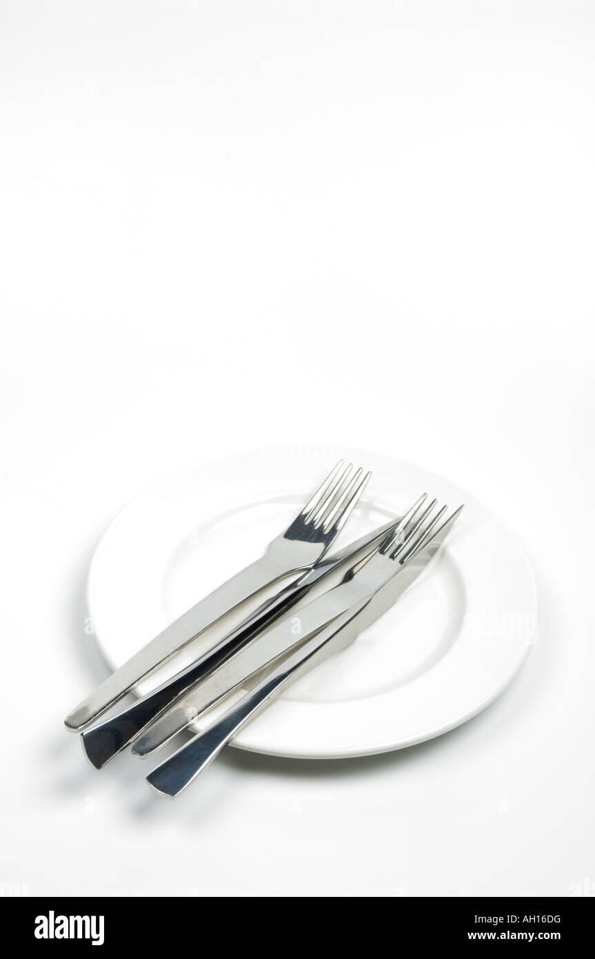Knives and forks on a white plate - table settings Stock Photo