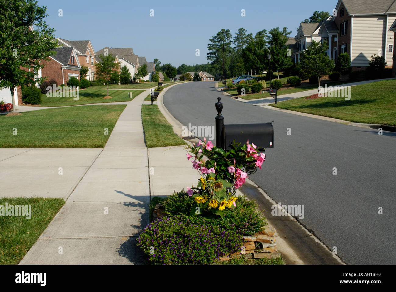 Suburban street neighborhood development with sidewalk, mailbox, flowers Stock Photo