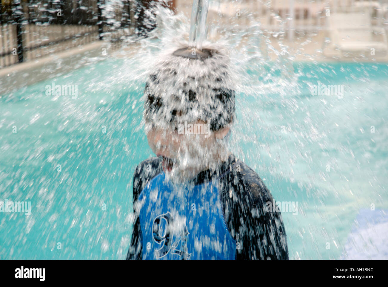 Boy under water cooling off at water park playground Stock Photo