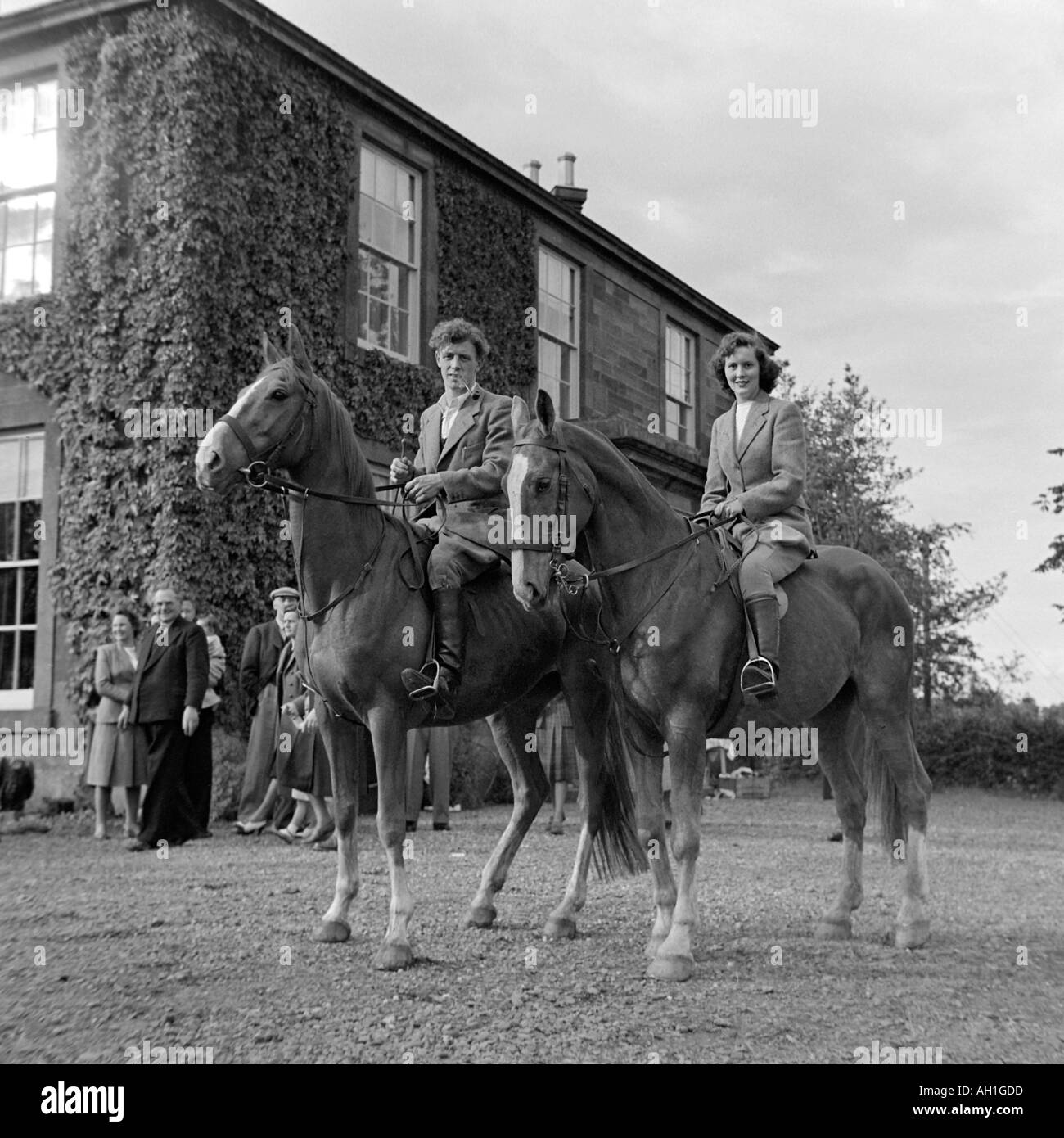 OLD VINTAGE FAMILY SNAPSHOT PHOTOGRAPH OF YOUNG MAN AND WOMAN WEARING TWEED COUNTRY CLOTHES SITTING ON HORSES Stock Photo