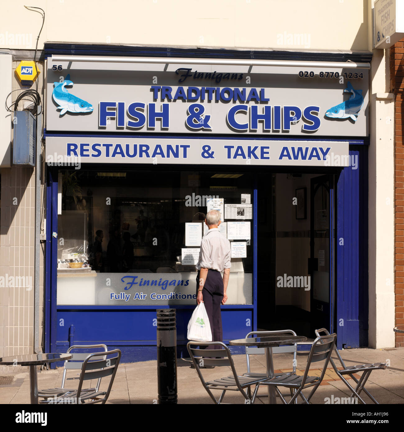 Man with Take Away Outside Fish Chip Shop Reading Notices in Window in  Sutton Surrey England Stock Photo - Alamy
