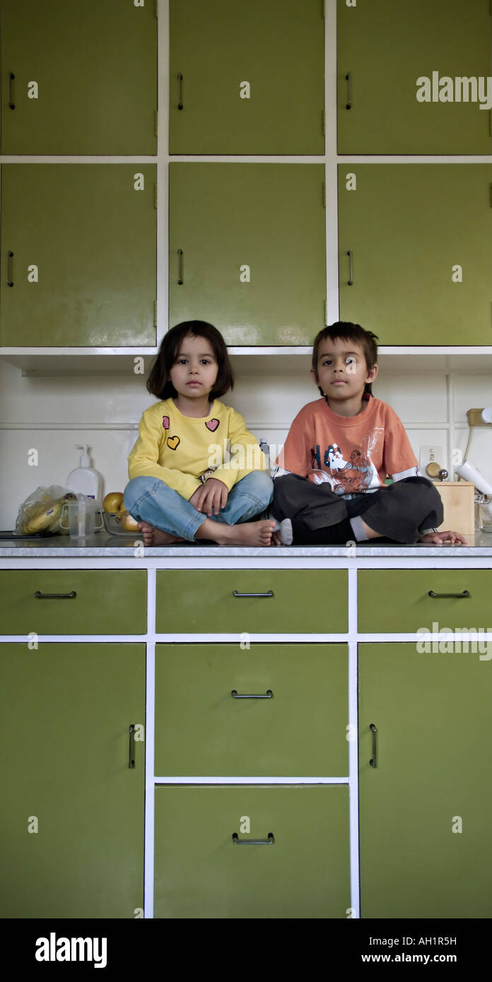 Children sit on kitchen worktop Stock Photo Alamy