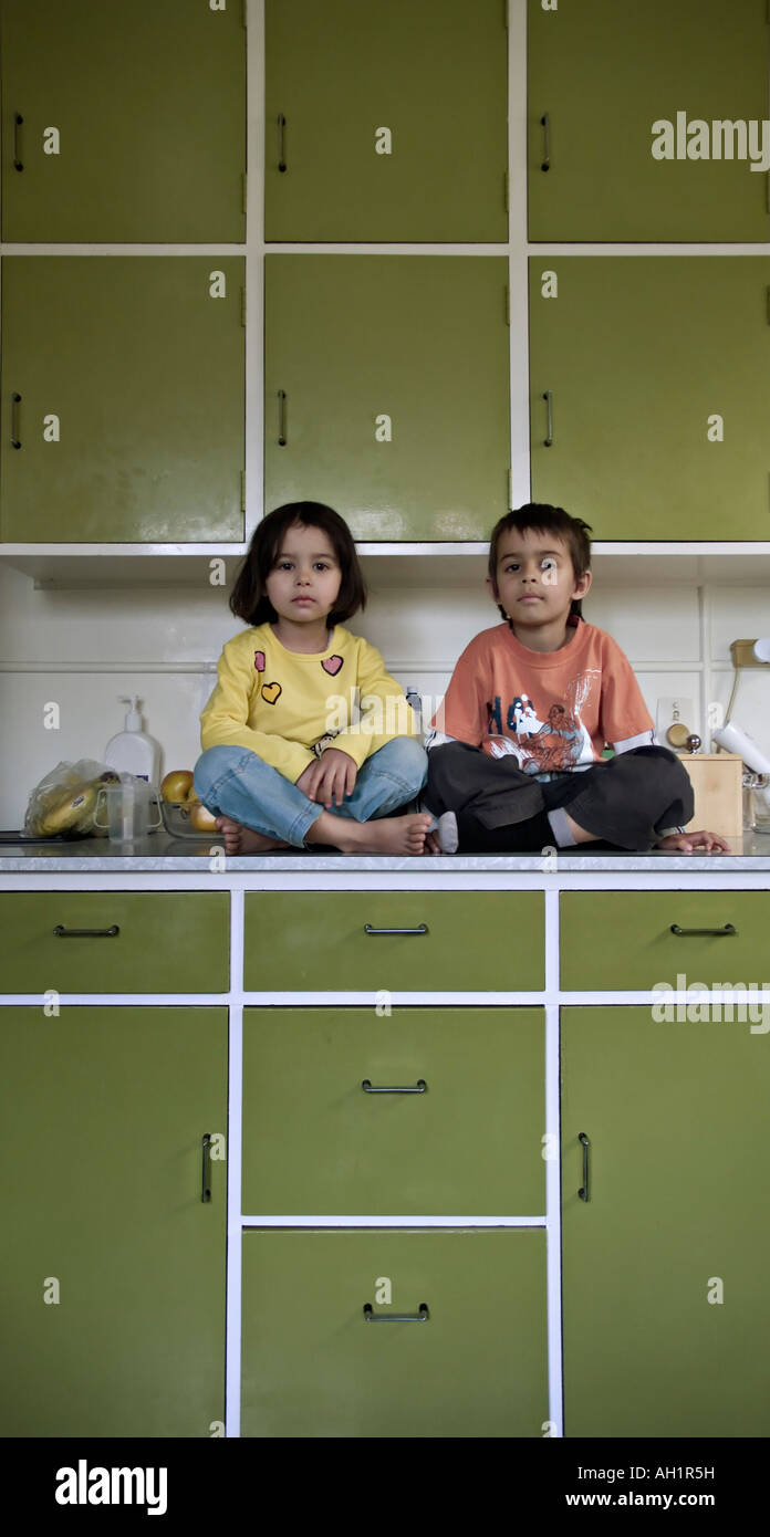 Children sit on kitchen worktop Stock Photo