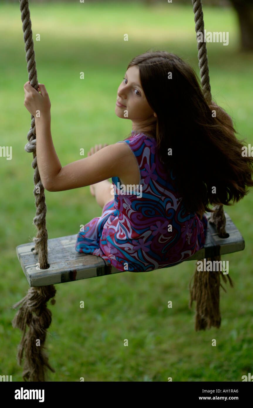 young girl sitting on a swing looking back Stock Photo - Alamy