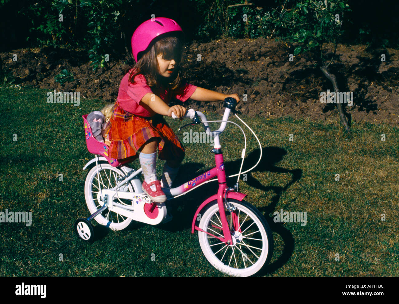 Child Riding Bike With Stabilisers And Cycle Helmet Stock Photo