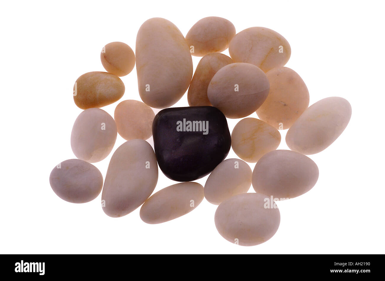 Smooth white beach stones surrounding one black stone, silhouette on white background Stock Photo