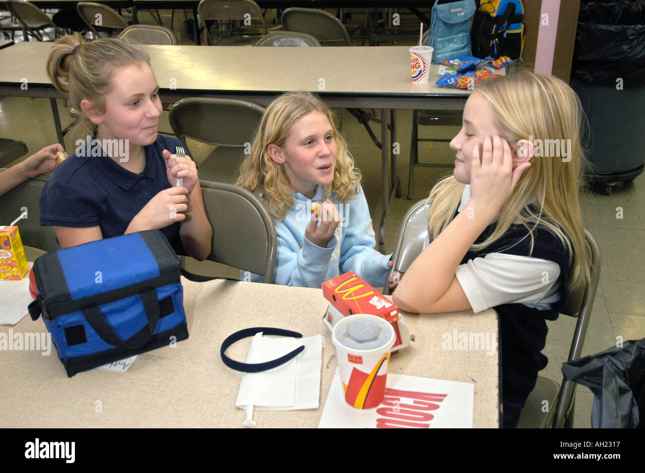 Girls socialize during lunch hour at school cafeteria Stock Photo