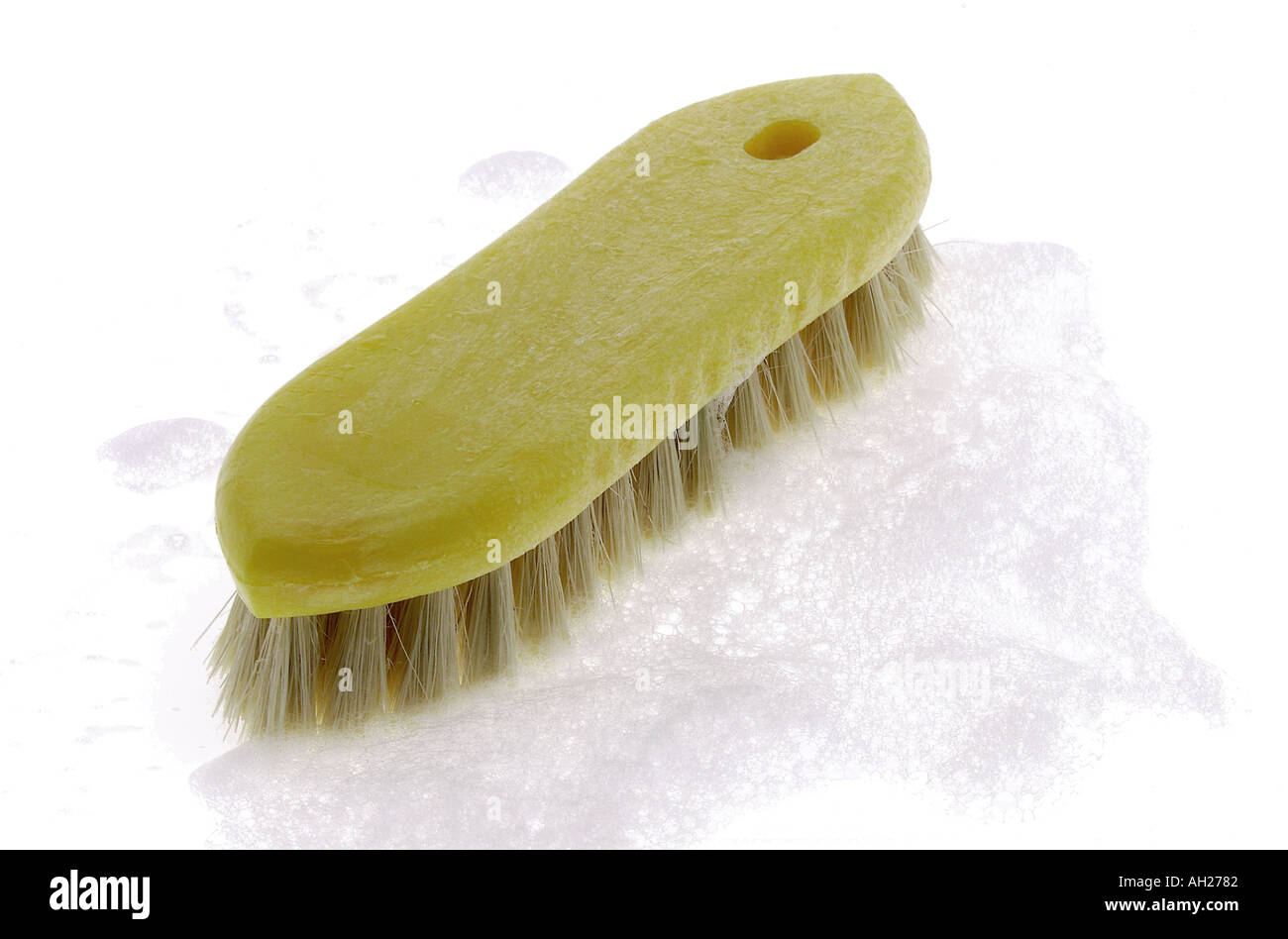 yellow scrub brush wth soap suds silhouetted on white background Stock Photo