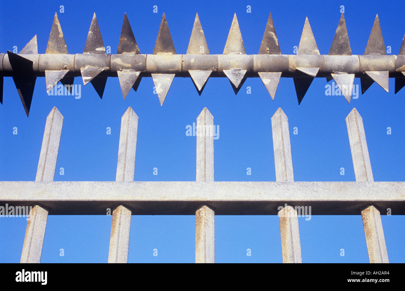 Detail of painted aluminium security railings with a row of angled metal teeth above them