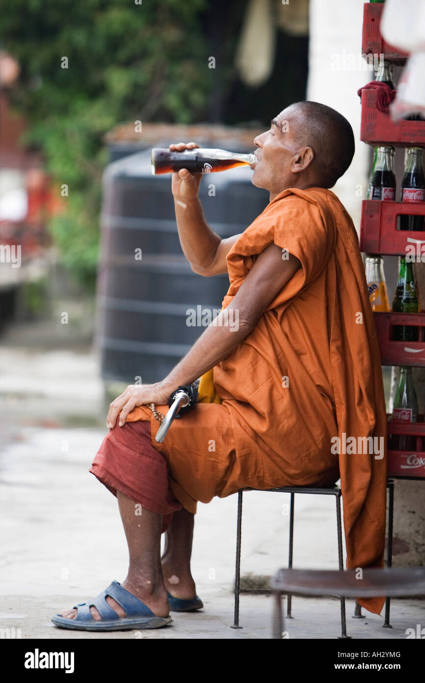 Buddhist monk drinking a bottle of coca cola. Kathmandu, Nepal Stock Photo