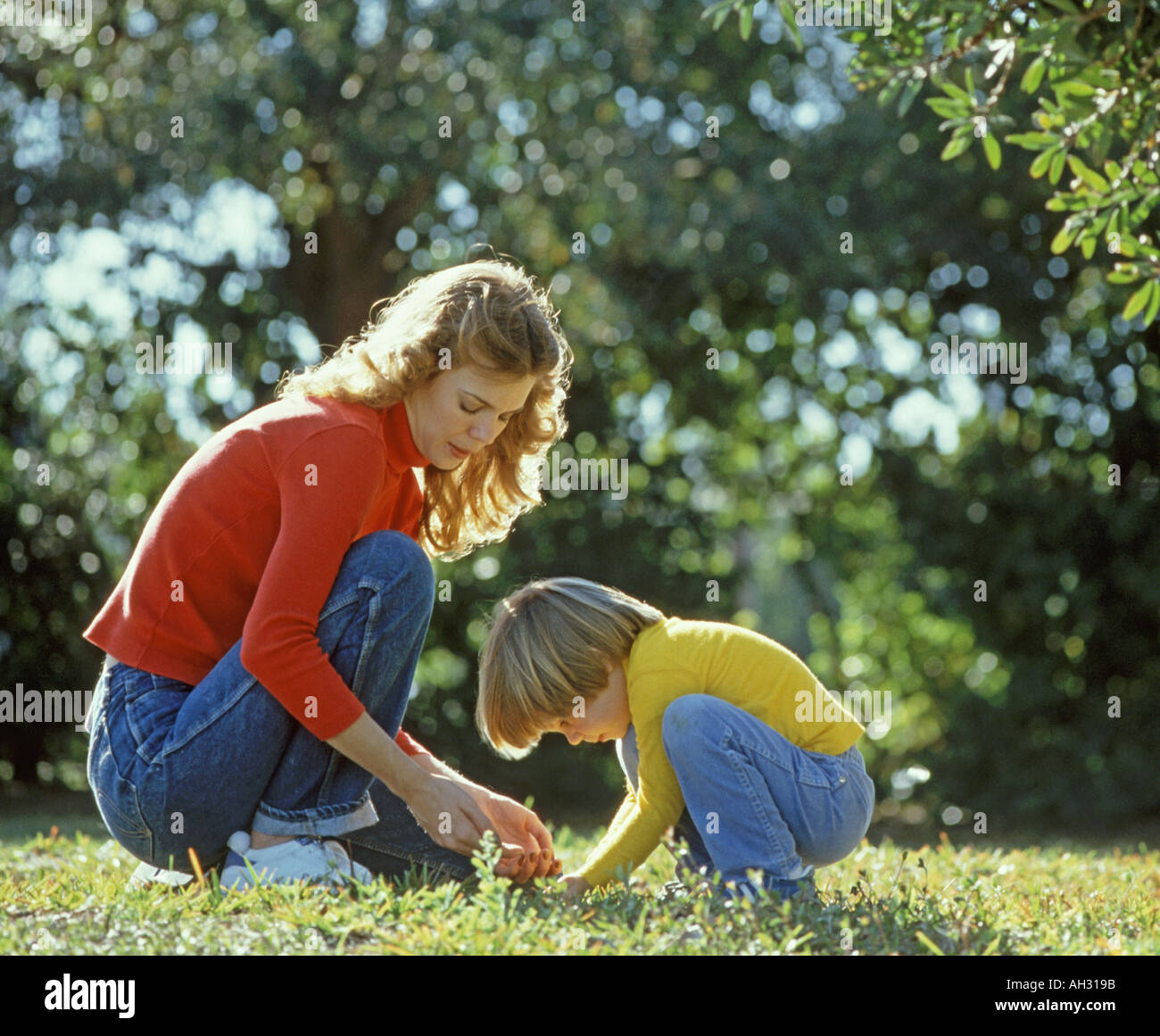 mother and small daughter exploring lawn Stock Photo