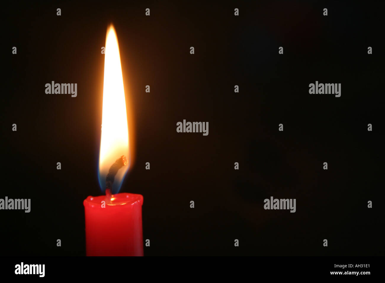 Red candle lit against black background Stock Photo Alamy