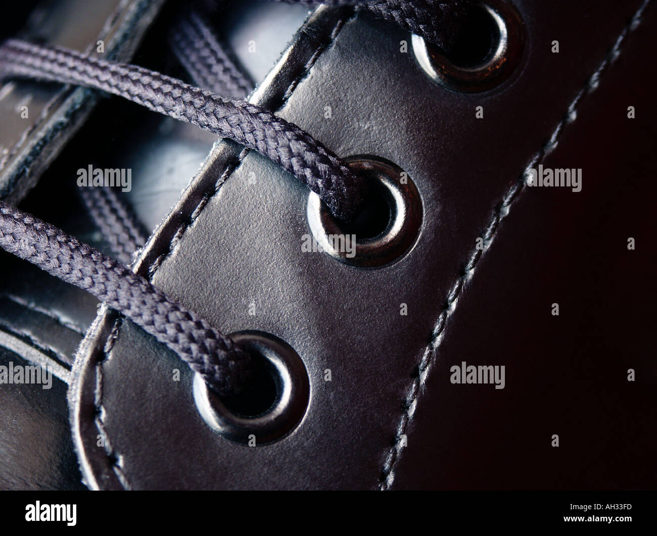 Boot Black Leather Lace Eyelet Close up Close Stitching Three Texture Smooth Polished tie weave tight cord pulled fasten Stock Photo