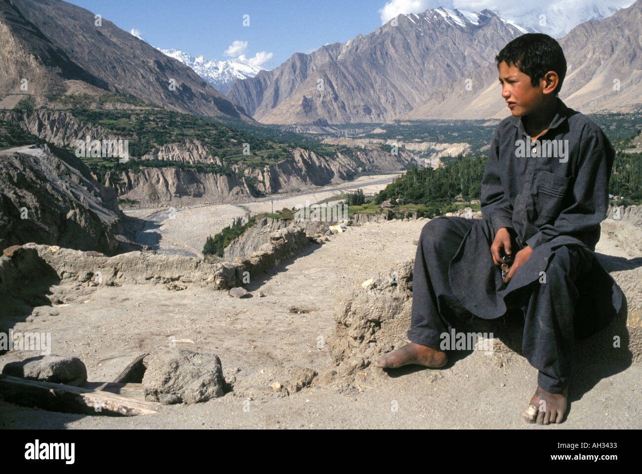 Young boy overlooking the Shandur Pass  in Pakistan,with the Himalaya mountains in the distance Stock Photo