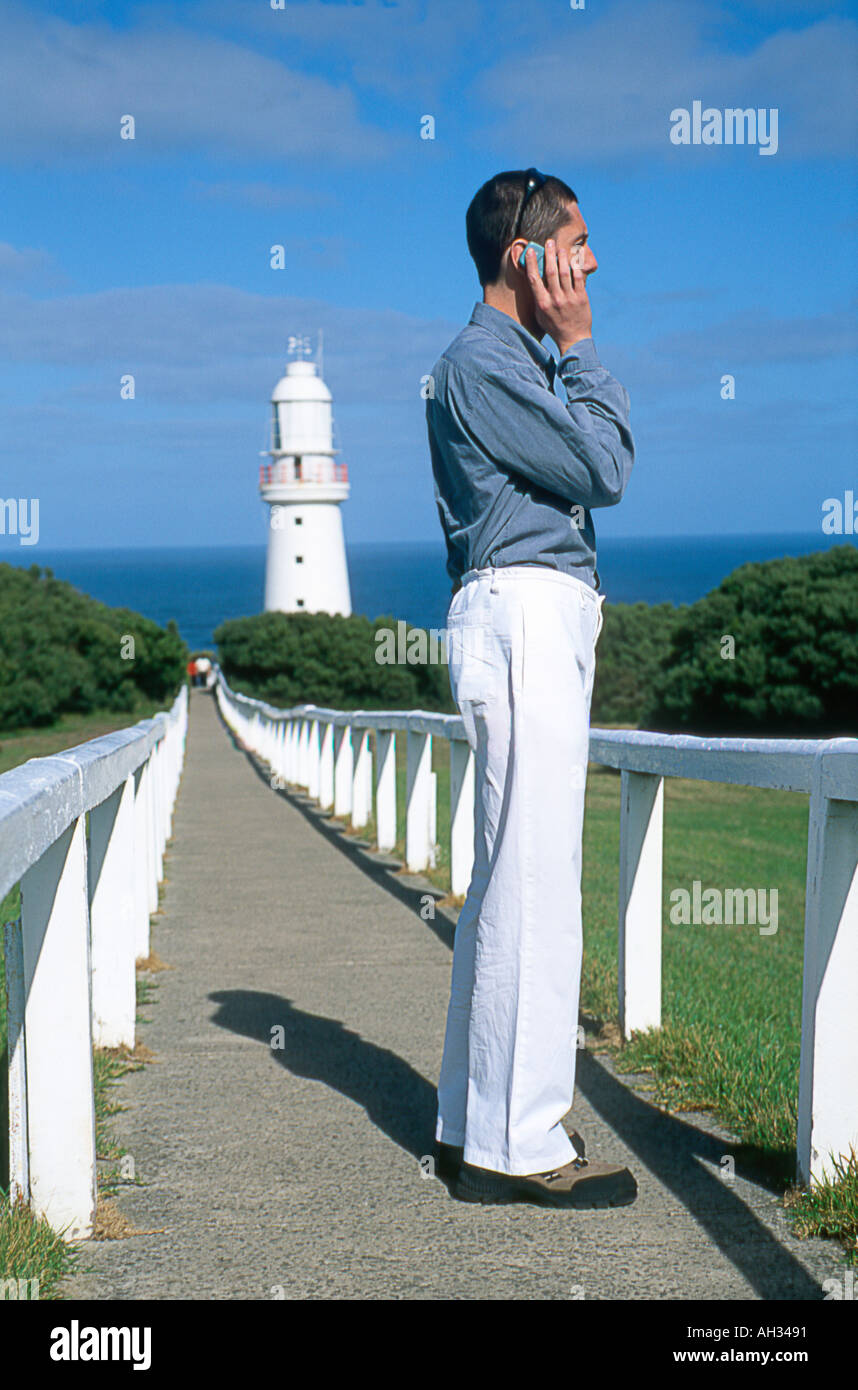 Man talking on a mobile phone near a lighthouse Stock Photo