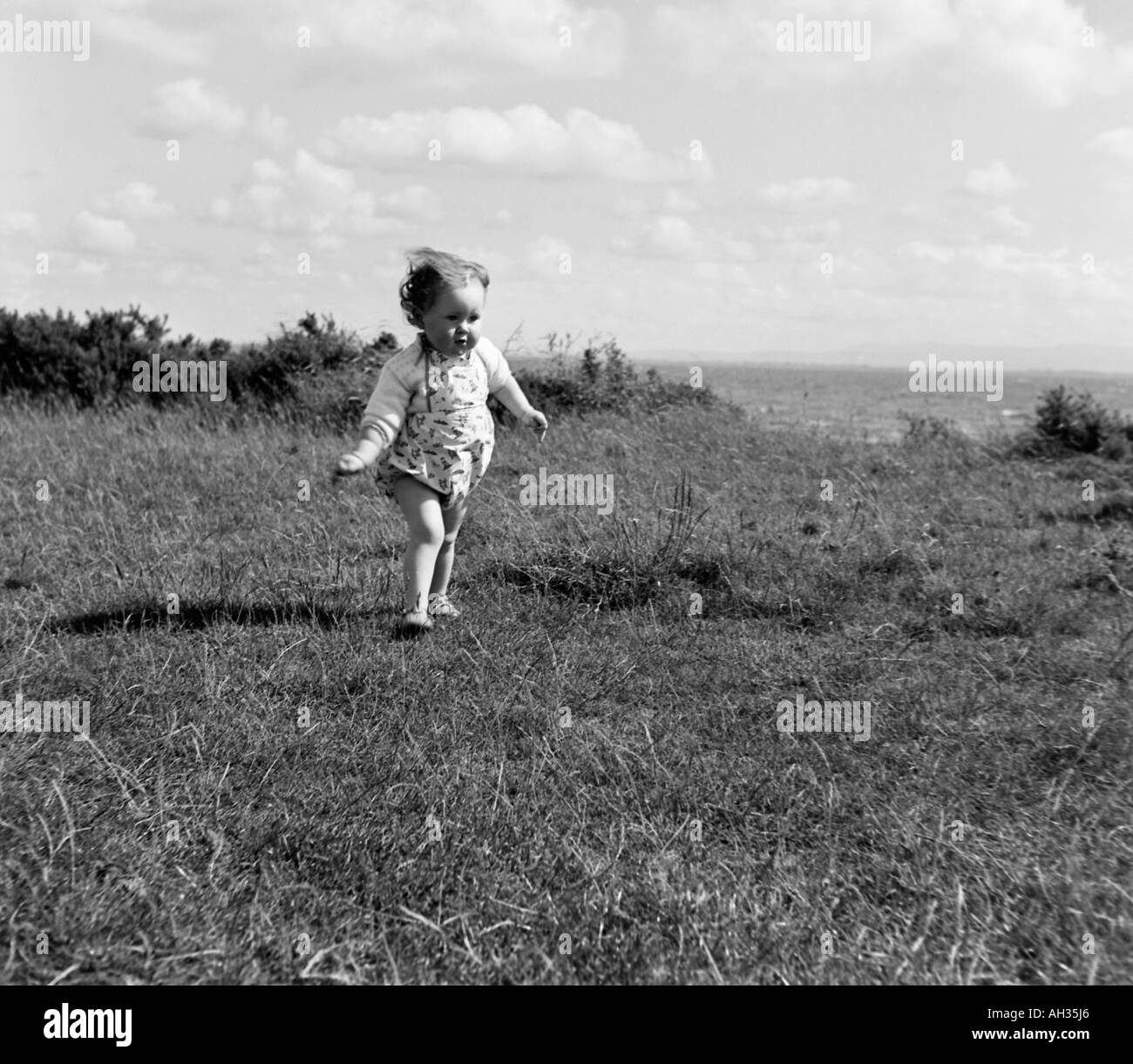 OLD VINTAGE FAMILY SNAPSHOT PHOTOGRAPH OF LITTLE GIRL RUNNING IN GRASS FIELD Stock Photo