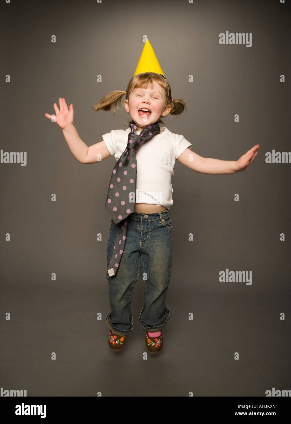 Little Girl Jumping In Tie And Party Hat Stock Photo Alamy