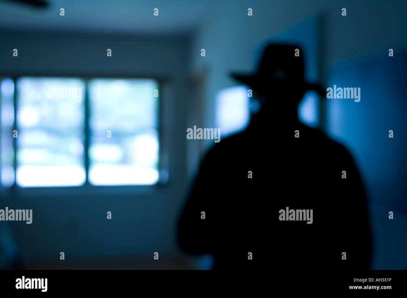 bad guy mystery man silhouetted in blurred room Stock Photo
