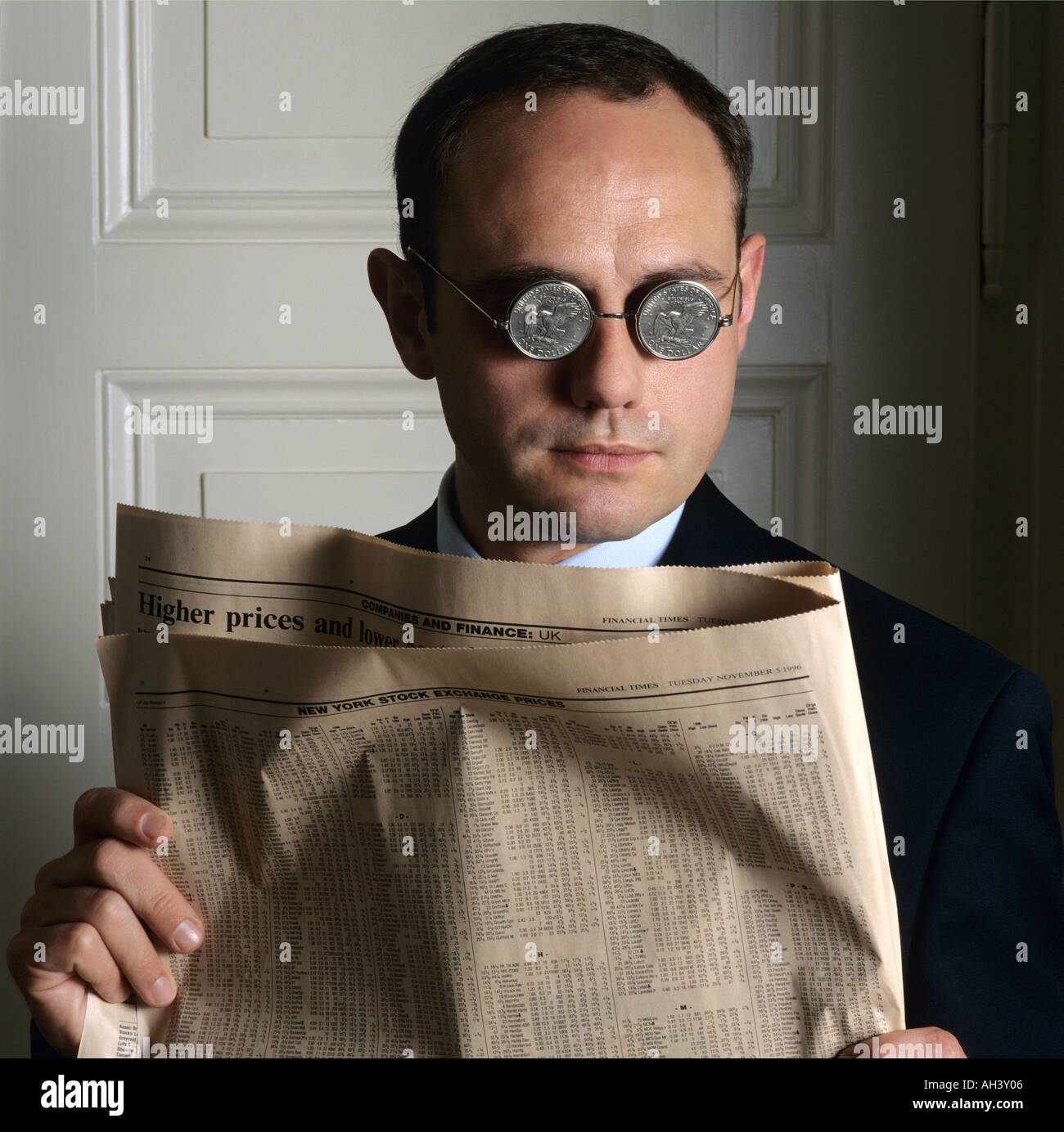 PORTRAIT OF A MAN WITH US DOLLAR COIN GLASSES AND FINANCIAL NEWSPAPER Stock Photo