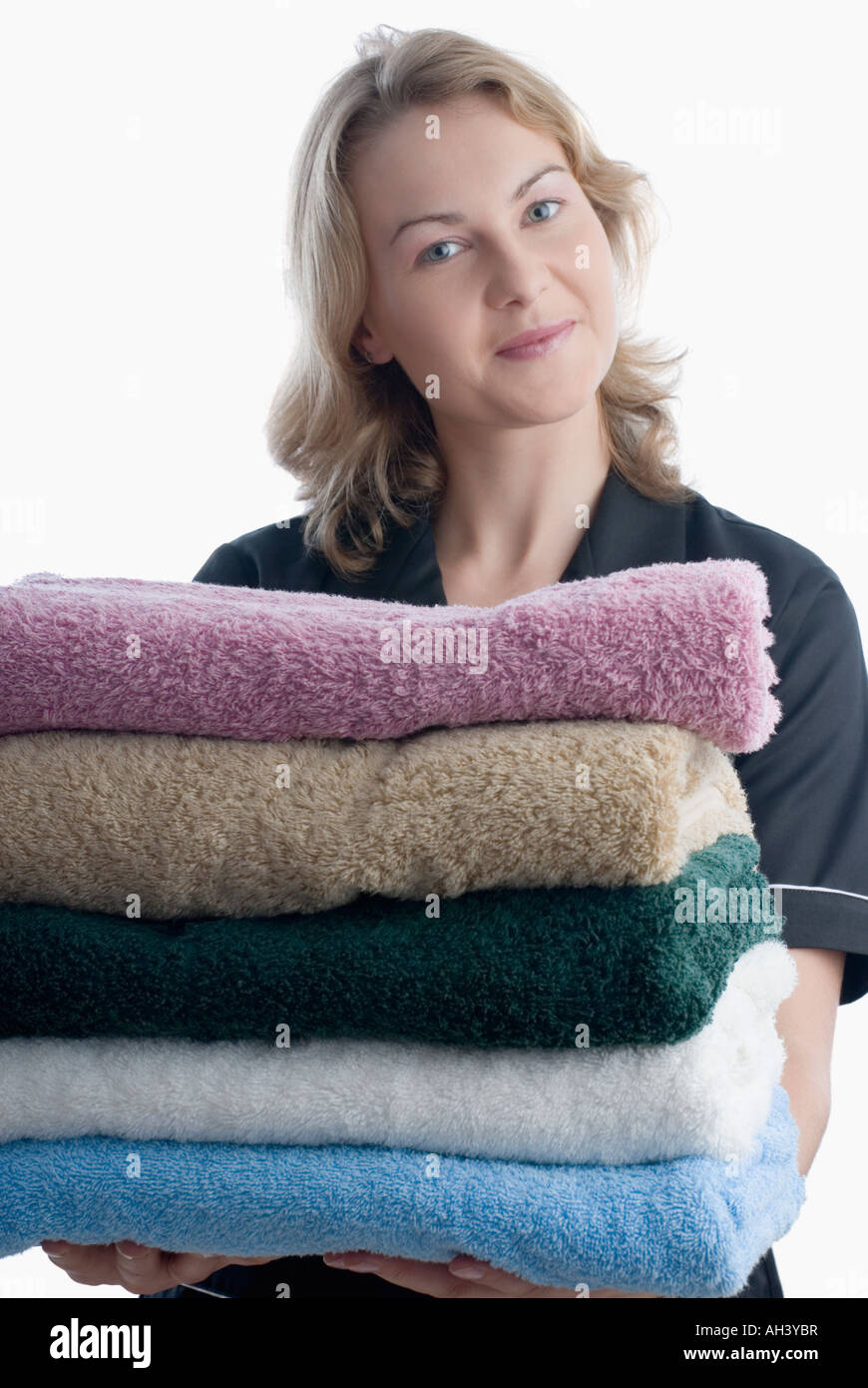 Portrait of a young woman holding a stack of towels Stock Photo - Alamy