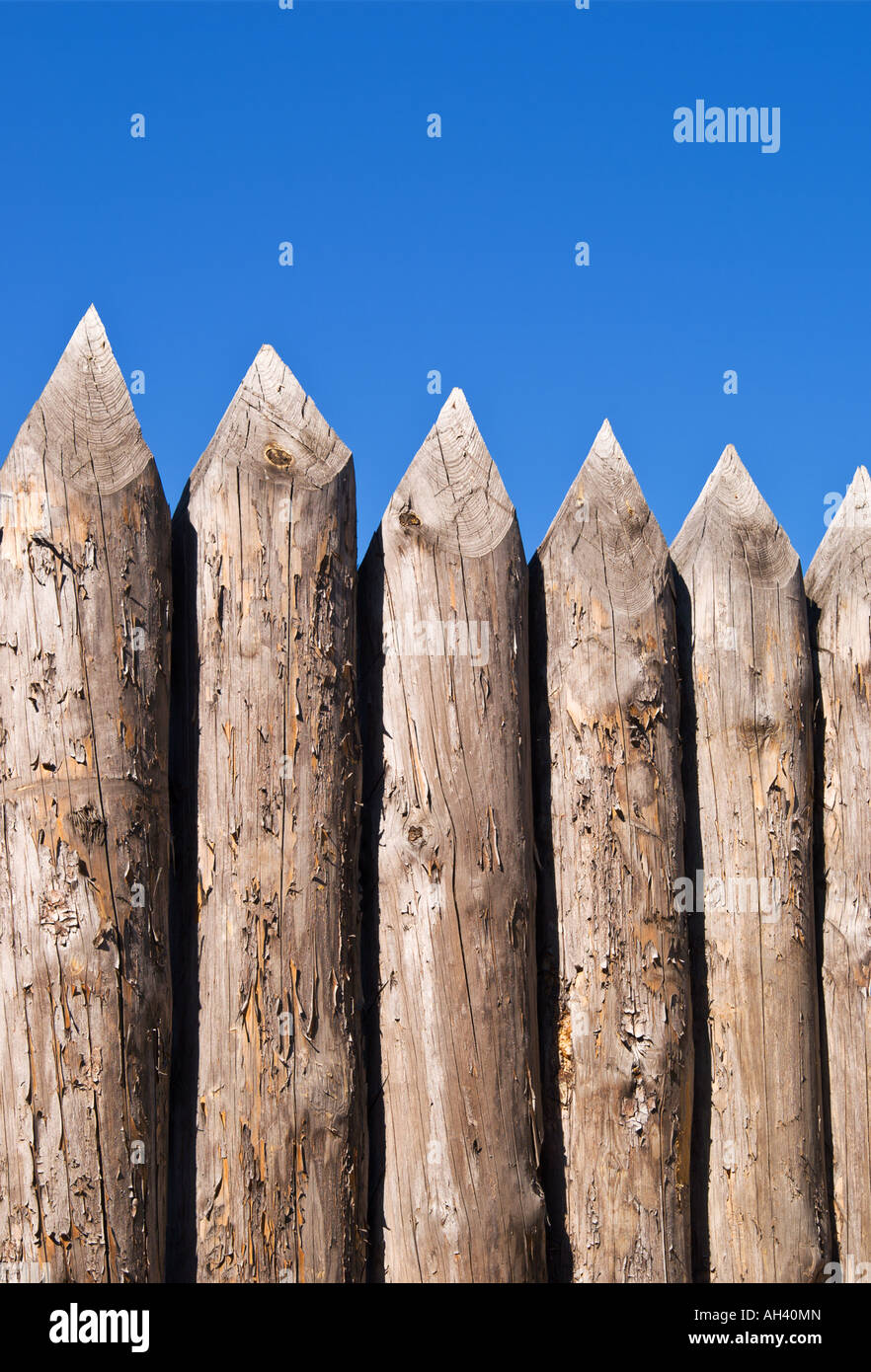 High wall of old wooden sharpened logs over blue sky Stock Photo
