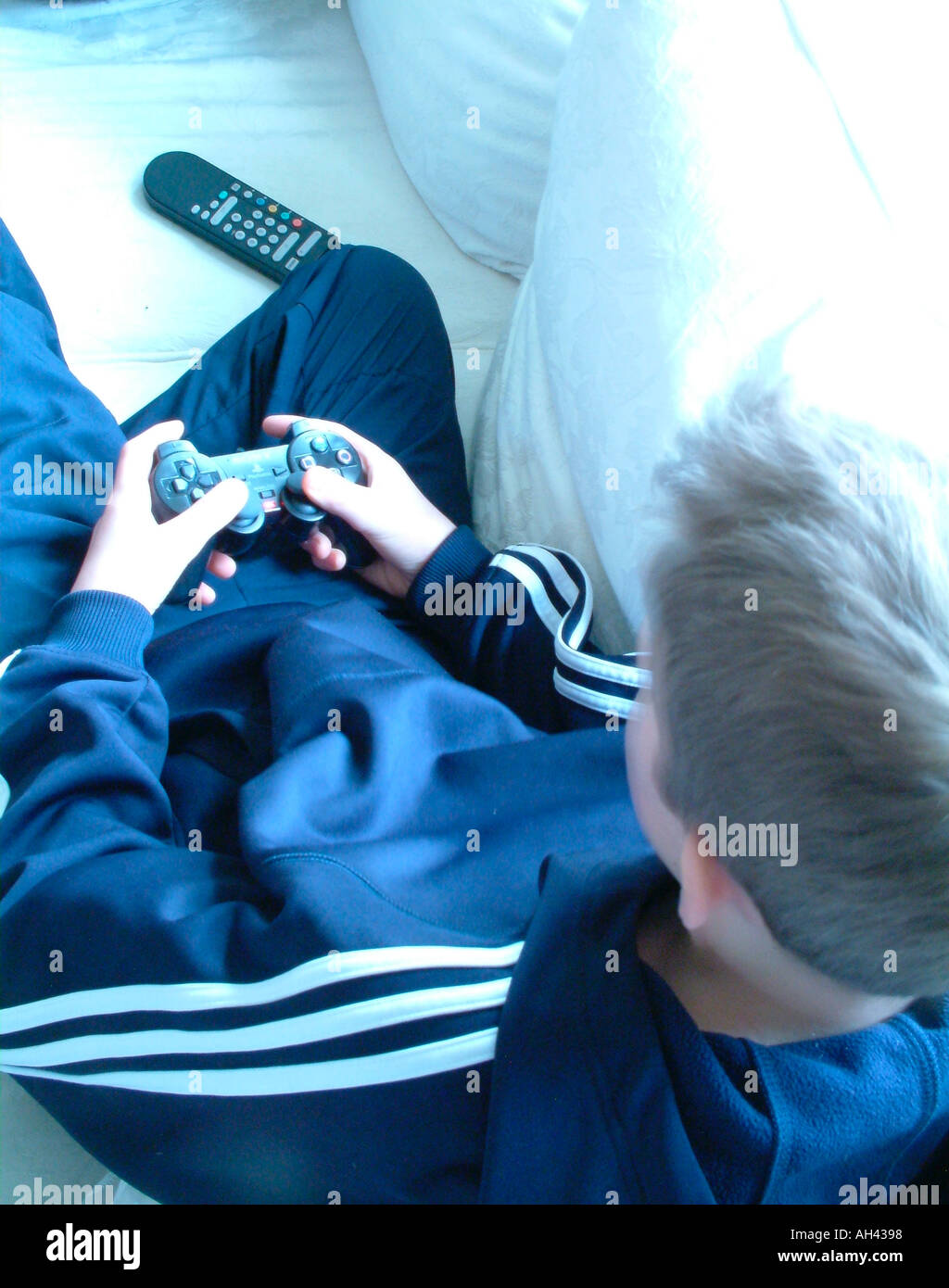 Crop on teenage boy and gamepad concentrating on screen screen not shown sitting on sofa Stock Photo