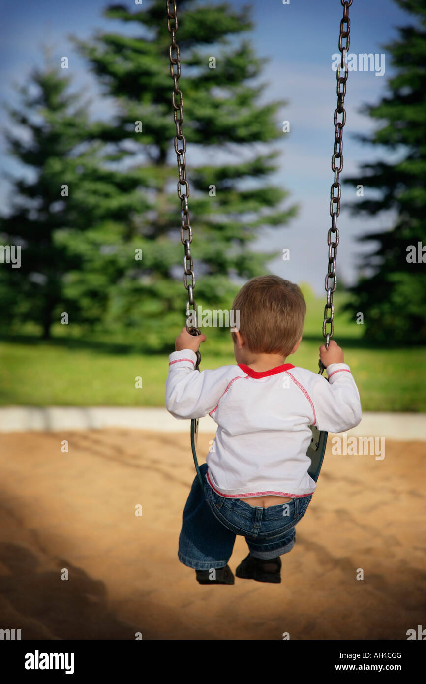 Little boy alone on a swing Stock Photo - Alamy