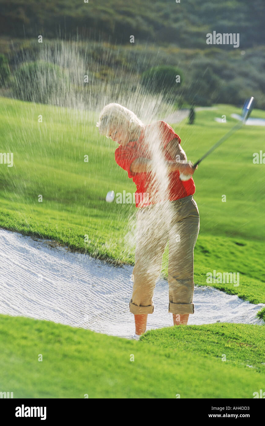 Woman golfer blasting shot out of sand trap or bunker Stock Photo