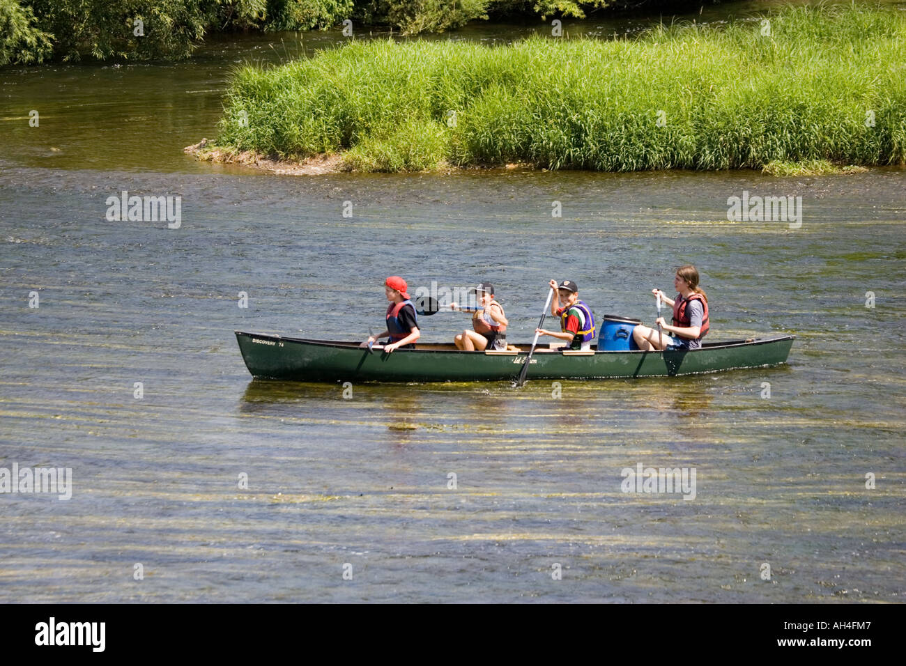 Woman and three boys paddling Canadian canoe down River Wye Lower