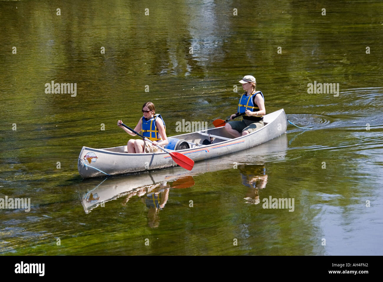 Two women paddling Canadian canoe down River Wye Lower Lydbrook UK