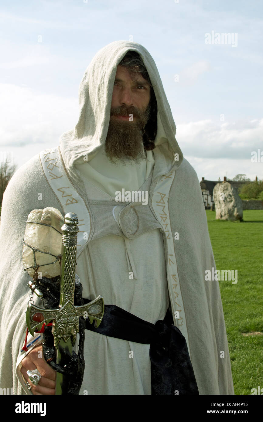 Merlin druid wizard pagan with hooded cloak and sword during Beltain festival at Avebury Ring Stone Circle neolithic monument site Wiltshire England Stock Photo