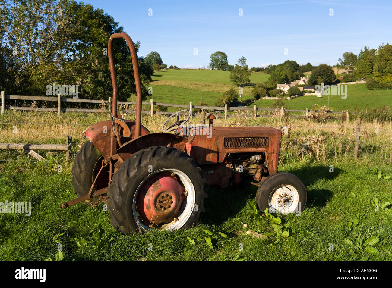 An old tractor lying in the evening sun above the Cotswold village of Middle Duntisbourne, Gloucestershire Stock Photo