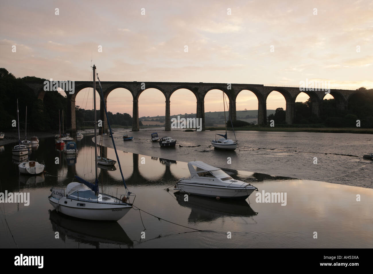 Early morning at low tide on the river Tiddy below the rail Viaduct with its quayside and boats at St Germans Stock Photo