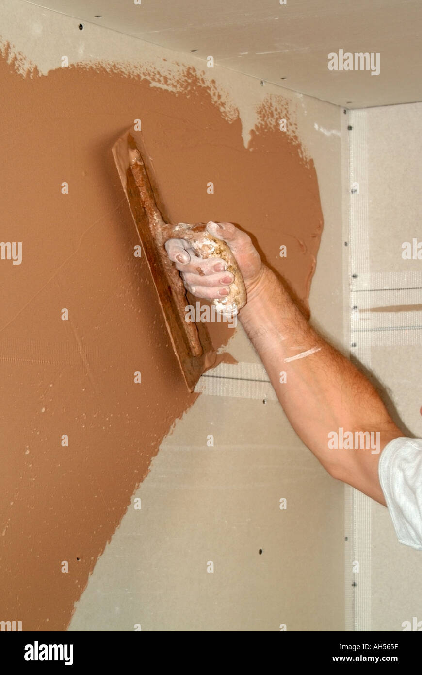 Alterations to form additional room plasterer at work applying setting coat to plasterboard wall Stock Photo
